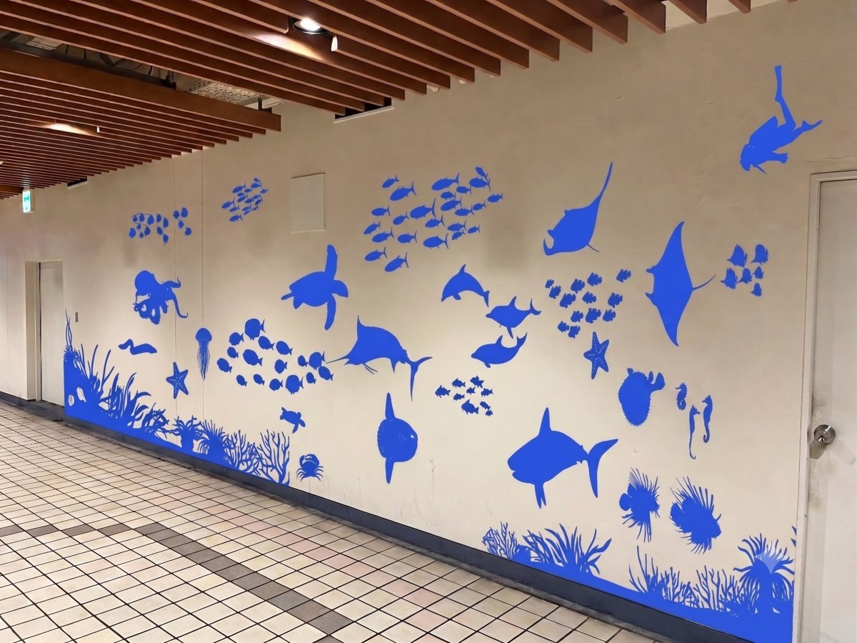 メトロこうべ中間通路の壁面に青いカッティングシートで描かれた海の生き物たち