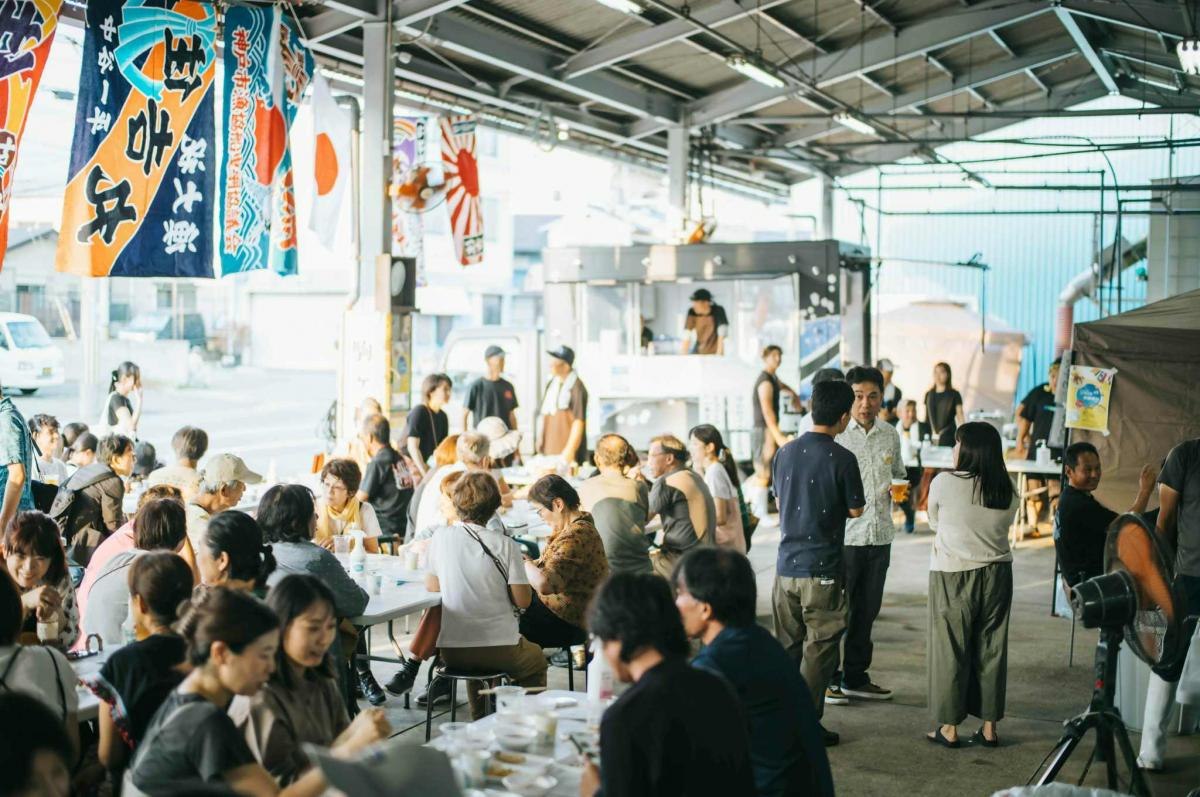 大漁旗が下がる会場で魚料理を味わう来場者