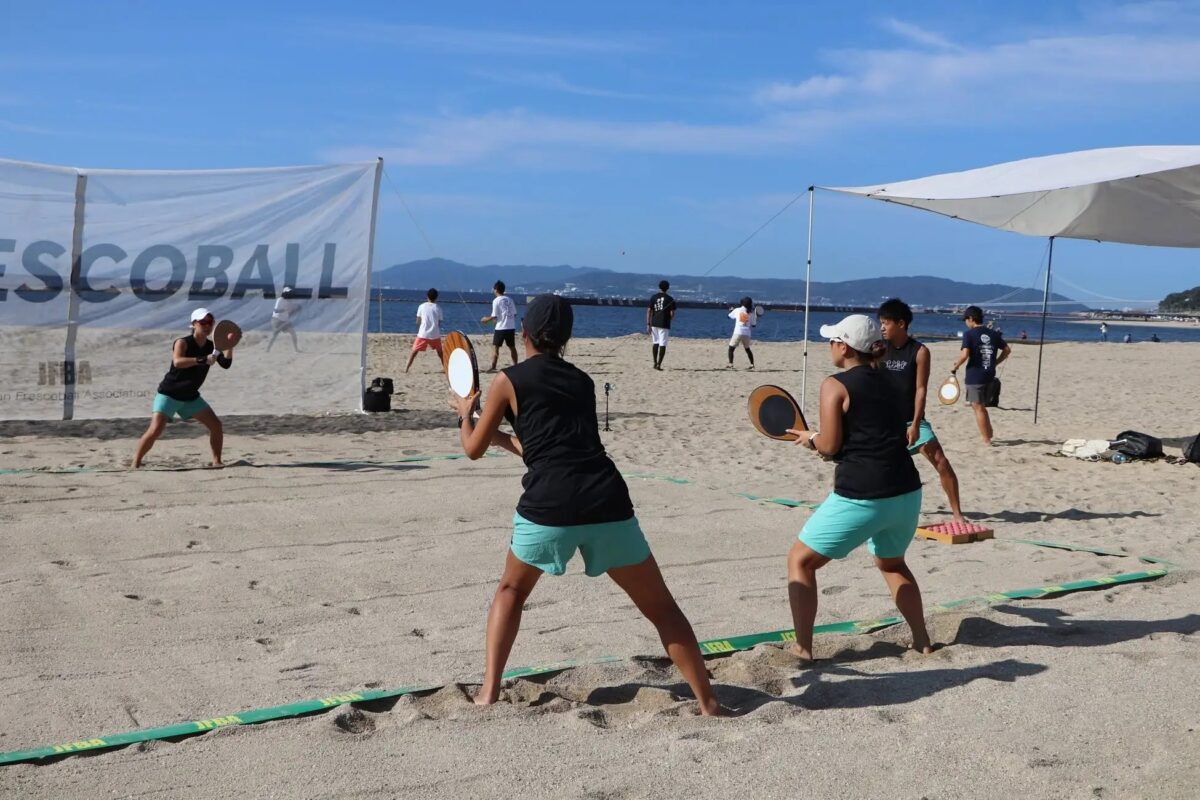 須磨海岸の砂浜でラケットを構えてラリーをするフレスコボールの選手たち