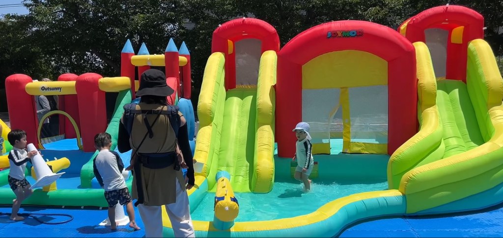 ふわふわウォータースライダーで水遊びをする子どもたち