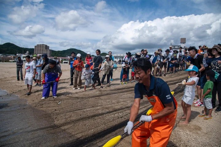 須磨海岸で地引網を引く漁師と参加者