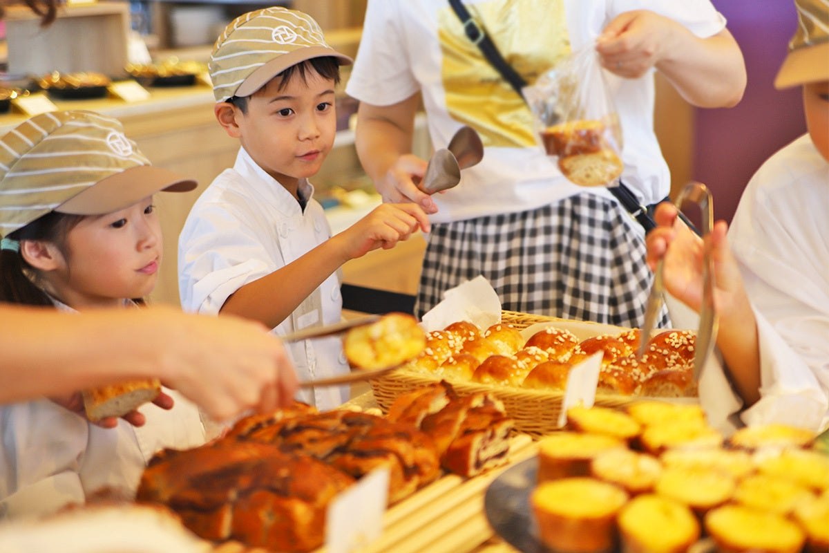 トングでお土産のパンを選ぶ子どもたち