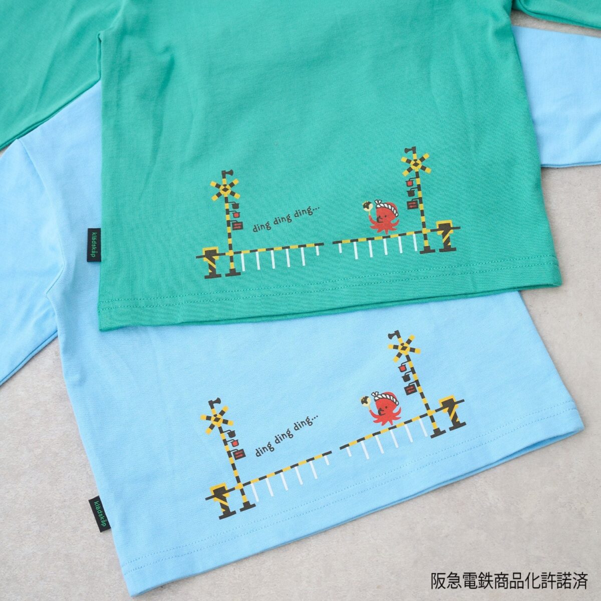 踏切とたこ焼きを持ったタコが描かれたTシャツの背面