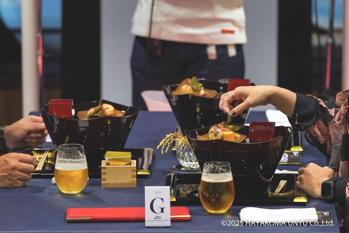船上のテーブルに並ぶ三段重と食器