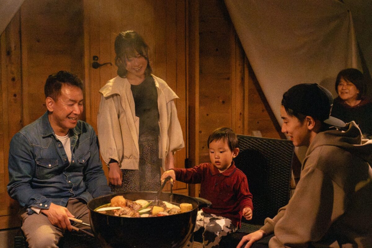 コテージの前でBBQを囲む家族